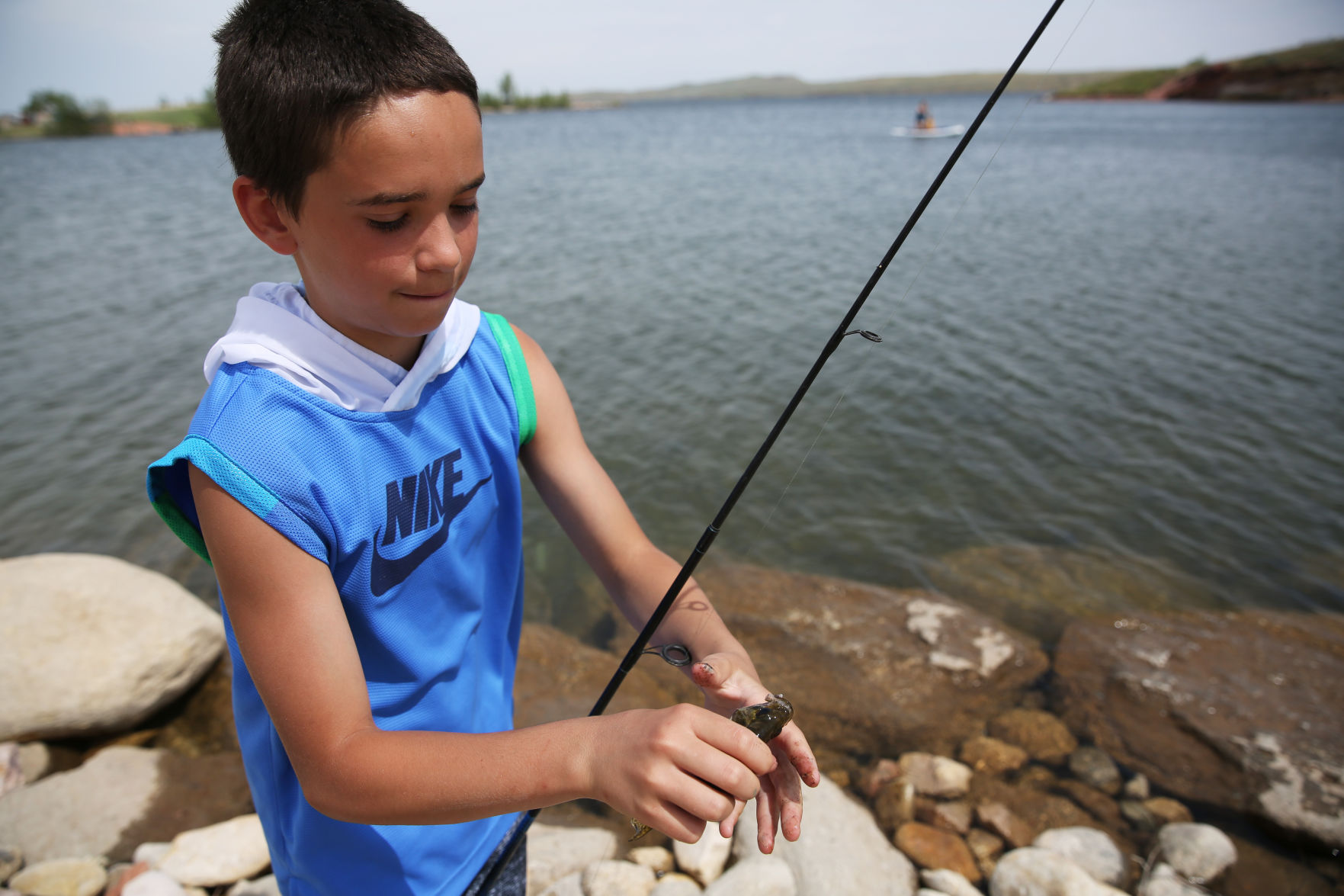Chase Ashcraft, 13, removes a small fish from his hook